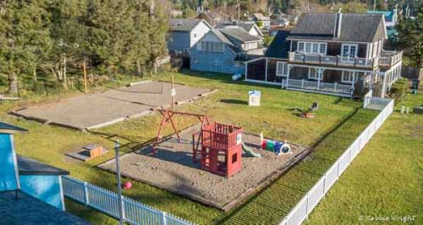1303 Beach Retreat is a favorite destination for families arial view of 1303 yard with playset and house in the background