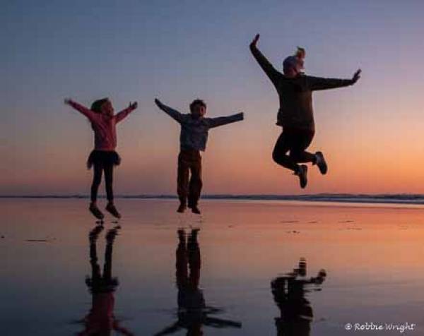 Families enjoy the beach more than anything else Woman and two small children silhouetted at sunset at the beach