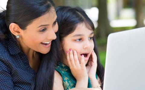 woman and young girl smiling at a computer screen