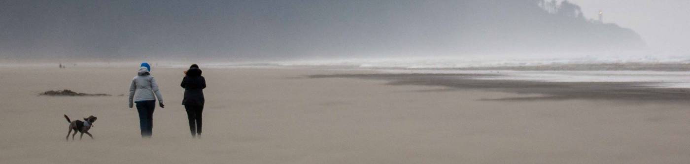 two people walking on the beach with northhead light house in the distance